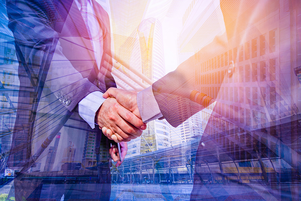 Agreement concept, showing 2 businessmen shaking hands overlaid with a business environment