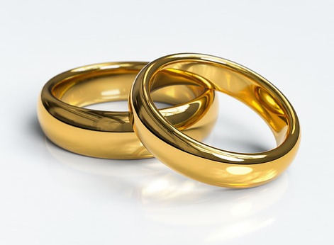 2 fine jewellery simple gold rings, on a reflective white surface