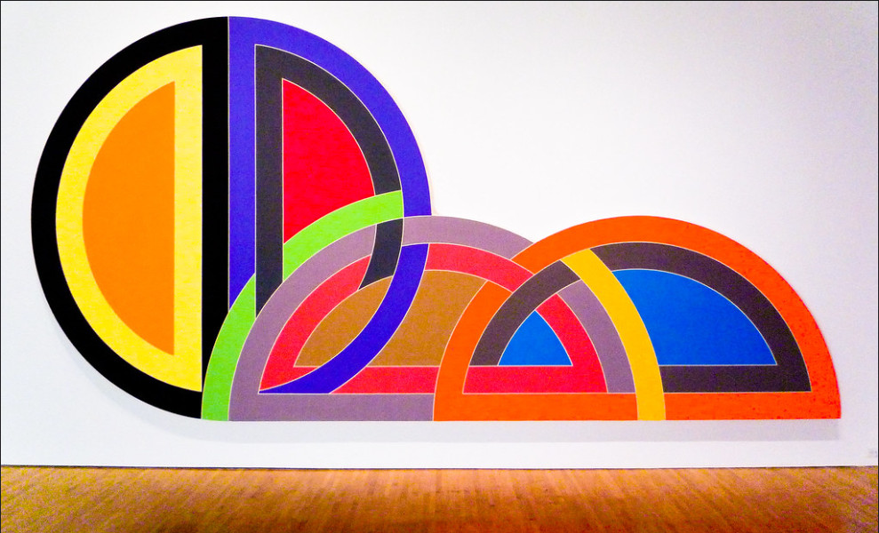 Frank Stella art, bright colours and curved shapes, in a gallery
