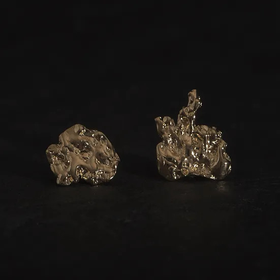 Art jewellery by Gaspard Hex, gold, organic shapes, on black surface.