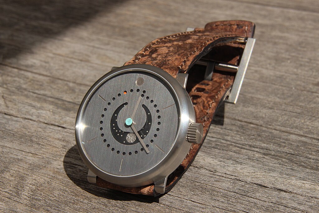 Ochs und Junior watch showing unpolished dial, in sunlight on wood surface.