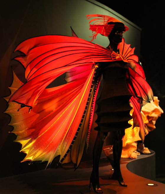 Susan Holmes wearable art, bright red fabric, on a mannequin, dark background