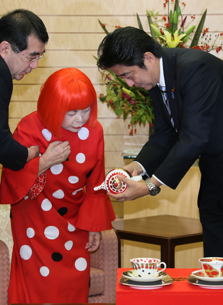 wearable art by Yayoi Kusama, bright red with big white spots, red hair.