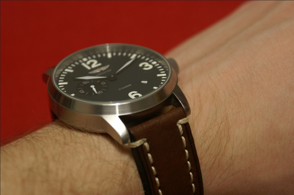 Aviator microbrand watch, worn on man's wrist ,red background.