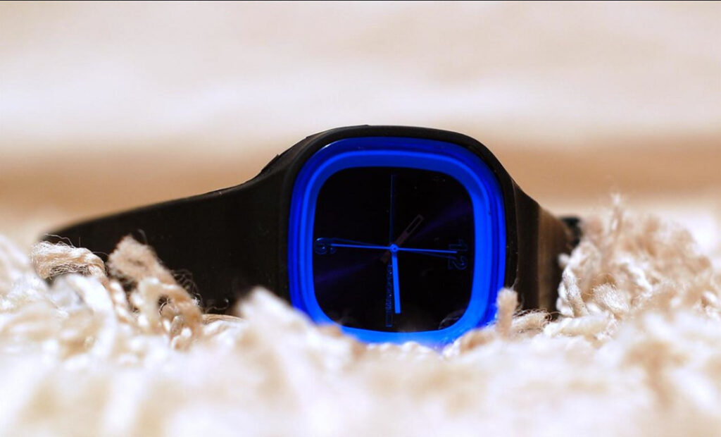 An example of blue watch aesthetic, a black and blue watch resting on a rough fabric, shallow depth of field.