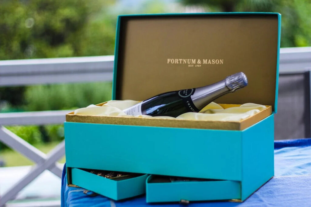 Fortunum and Mason, blue gift box including bottle of alcohol, on a table outdoors - a British luxury brand.