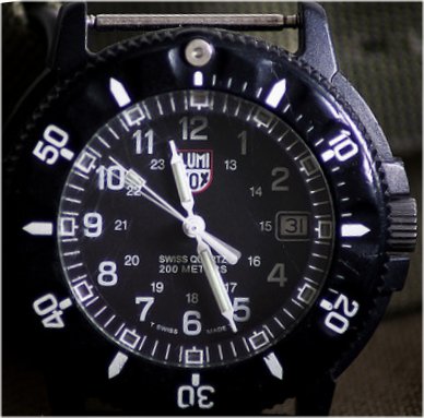 Luminox Navy Seals watch, mostly black with white numerals and markers, against a brown background.