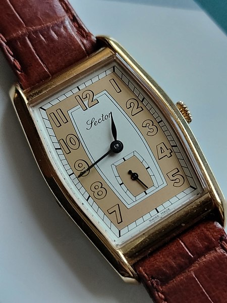 Sector watch - art deco watch aesthetics, gold and white colours, on white surface.