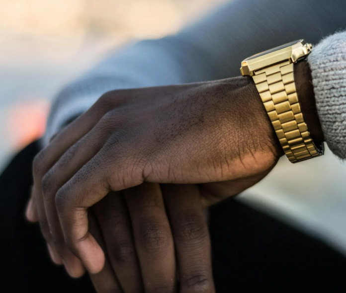 Contemporary gold watch with gold strap, worn on a man's wrist.