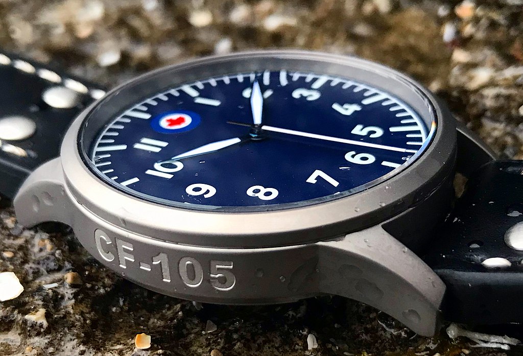 Avro CF105 Arrow Pilot Watch by WWCo. with a dark blue dial, on a rough surface.