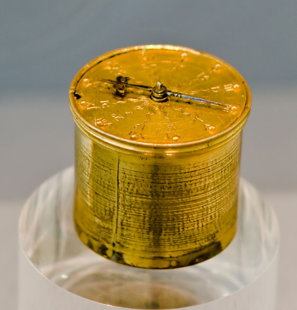 Henlein Taschenuhr small clock, cylindrical shape, yellow metal, on a transparent display stand.