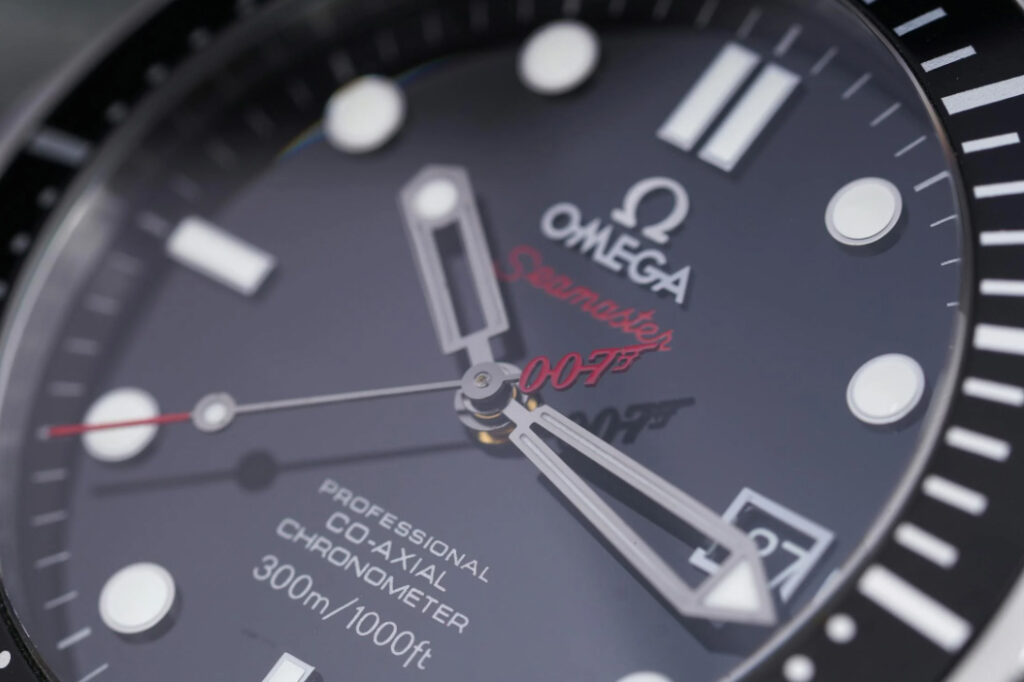 Omega Seamaster watch with a black dial and red accents, closeup/detail.