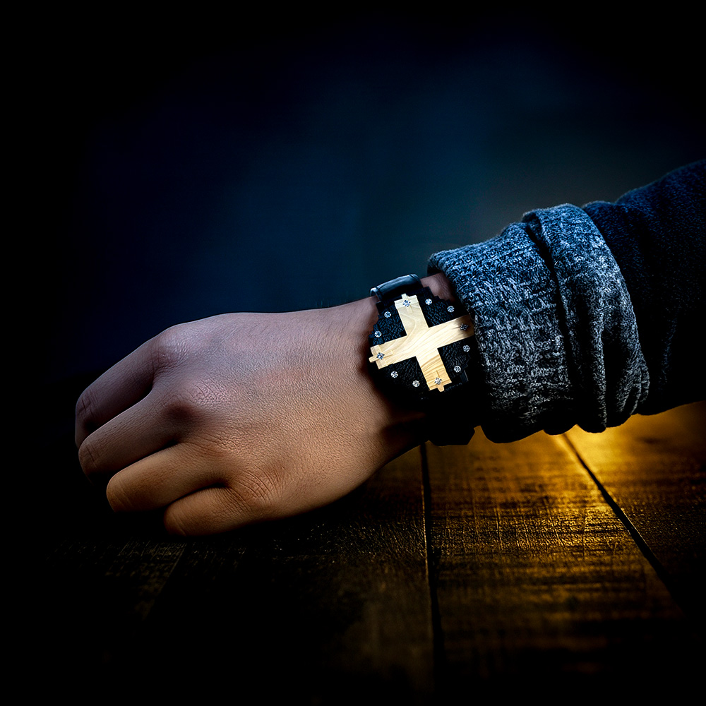 Cross #1 wristwatch worn on the wrist with a wooden table, yellow light and dark background