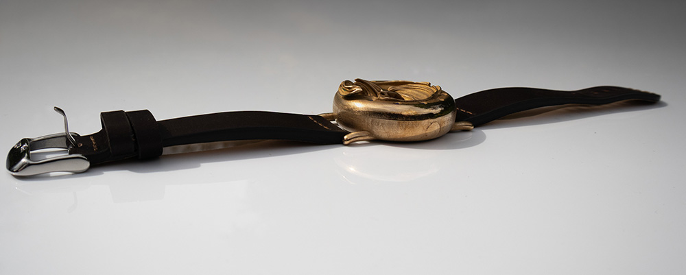 UnconstrainedTime Fractal Emergence wristwatch, side view with brown leather strap, on a reflective white surface.