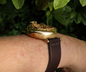 UnconstrainedTime Fractal Emergence wristwatch, bronze, side view on wrist, with foliage.