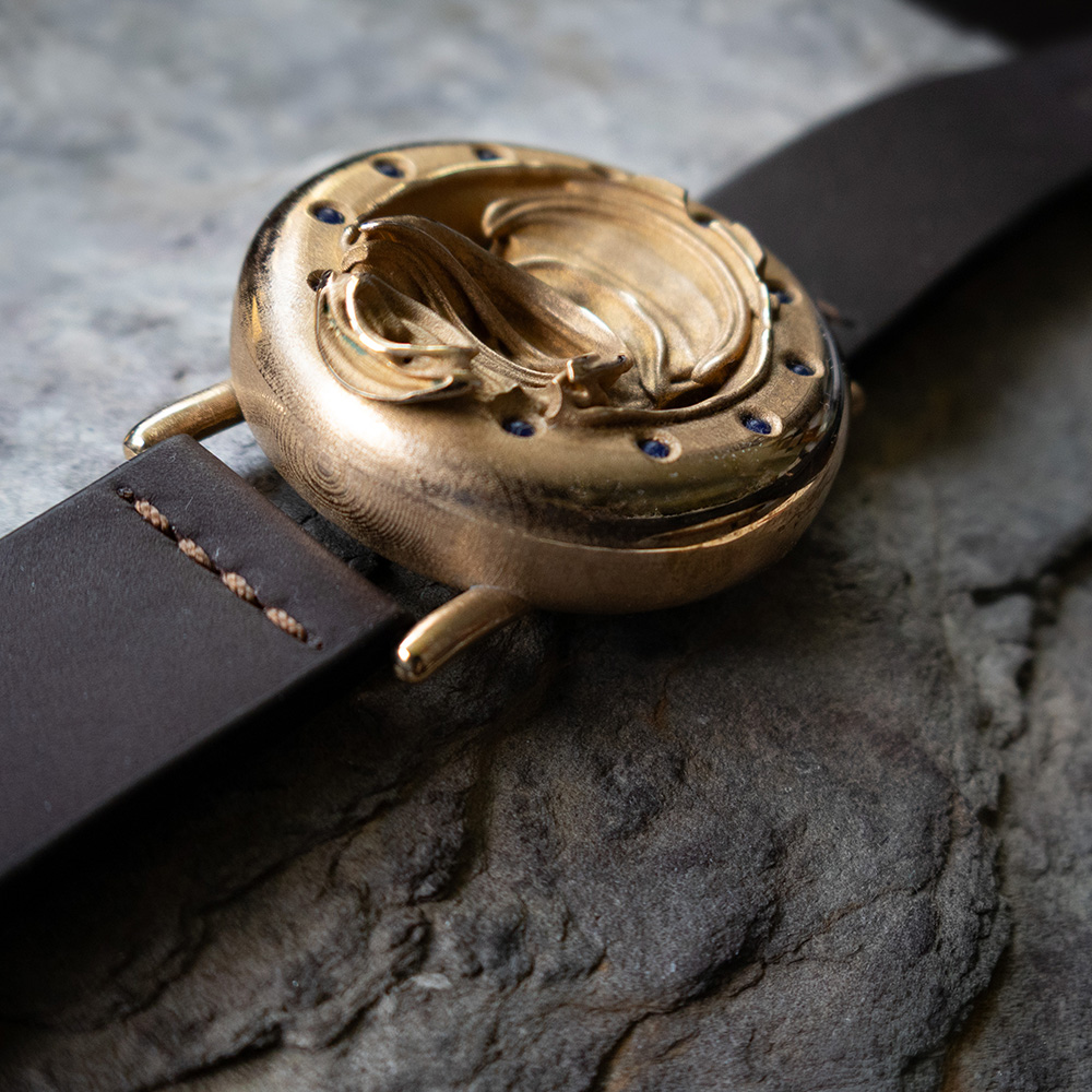 UnconstrainedTime Fractal Emergence 41mm wristwatch in bronze, hero shot on stone surface.