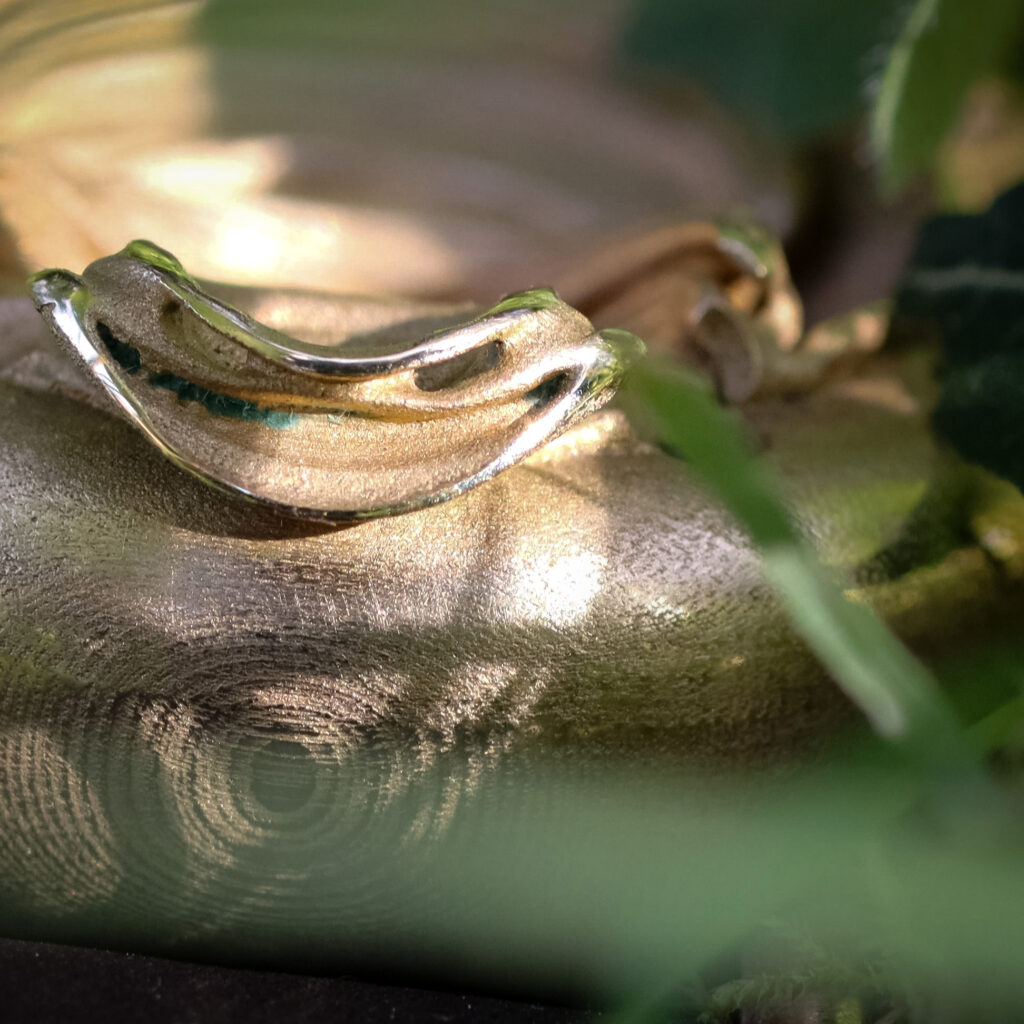 UnconstrainedTime Fractal Emergence 41mm wristwatch in bronze, closeup through grass showing the head of the fractal.