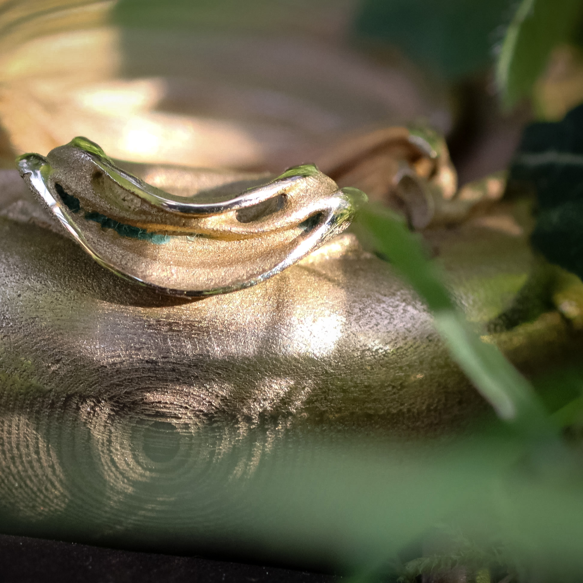 UnconstrainedTime Fractal Emergence 41mm wristwatch in bronze, closeup through grass showing the head of the fractal.