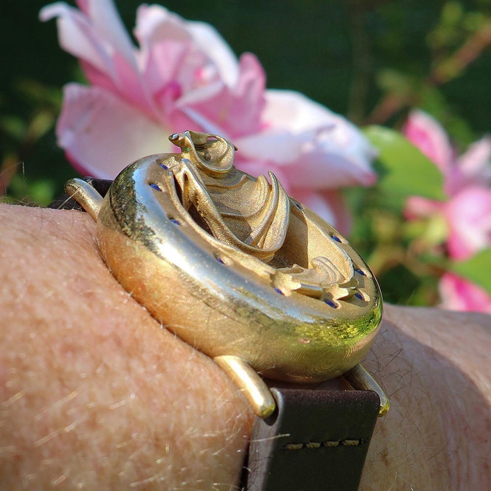 UnconstrainedTime Fractal Emergence 41mm wristwatch in bronze, on a wrist, sunlit with a rose.
