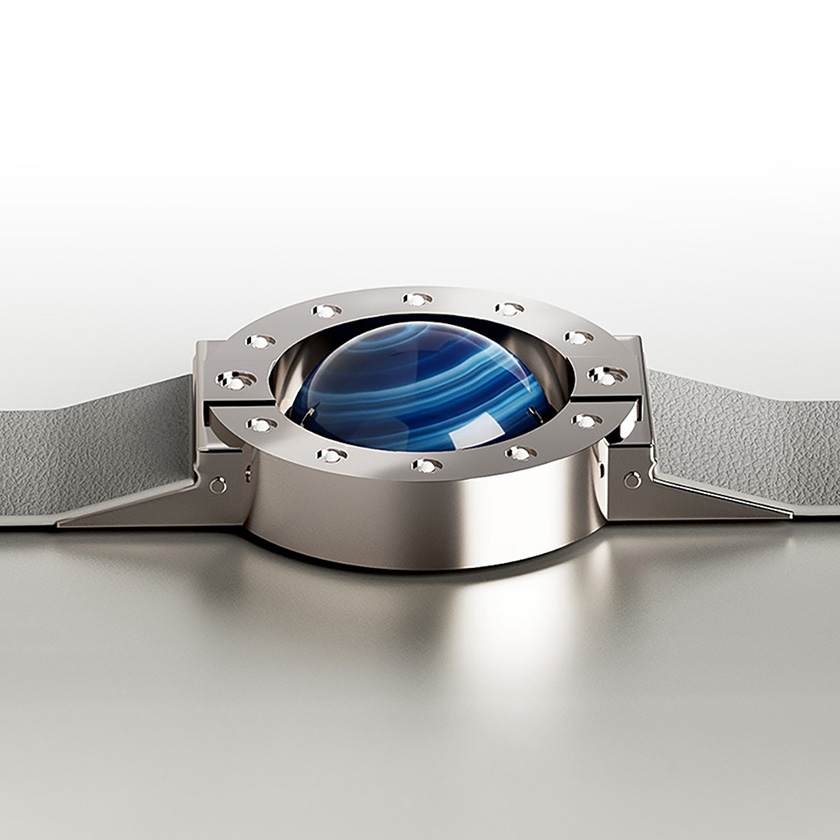 Stone-hold watch in silver with agate cabochon on a reflective surface.