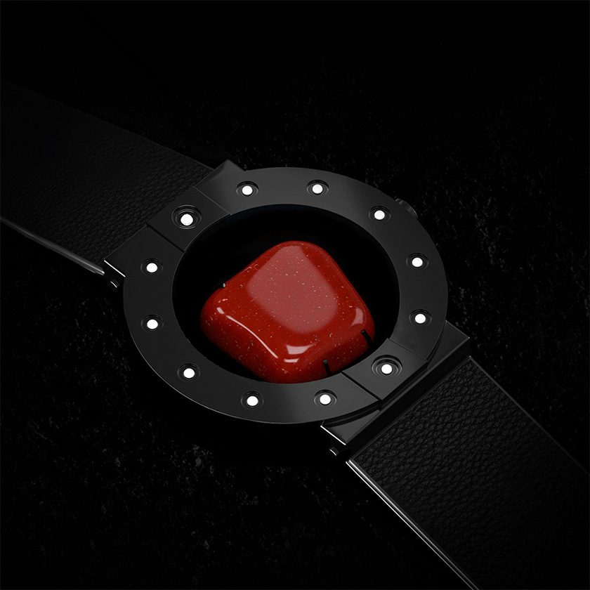 Stone-hold wristwatch in black with red jasper on a rough black surface.
