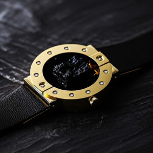 Stone-hold watch in gold with black lava on a rough black stone surface.